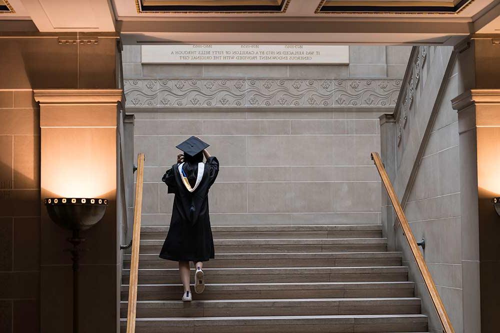 学生戴着帽子和长袍走上拉什·里斯图书馆的楼梯