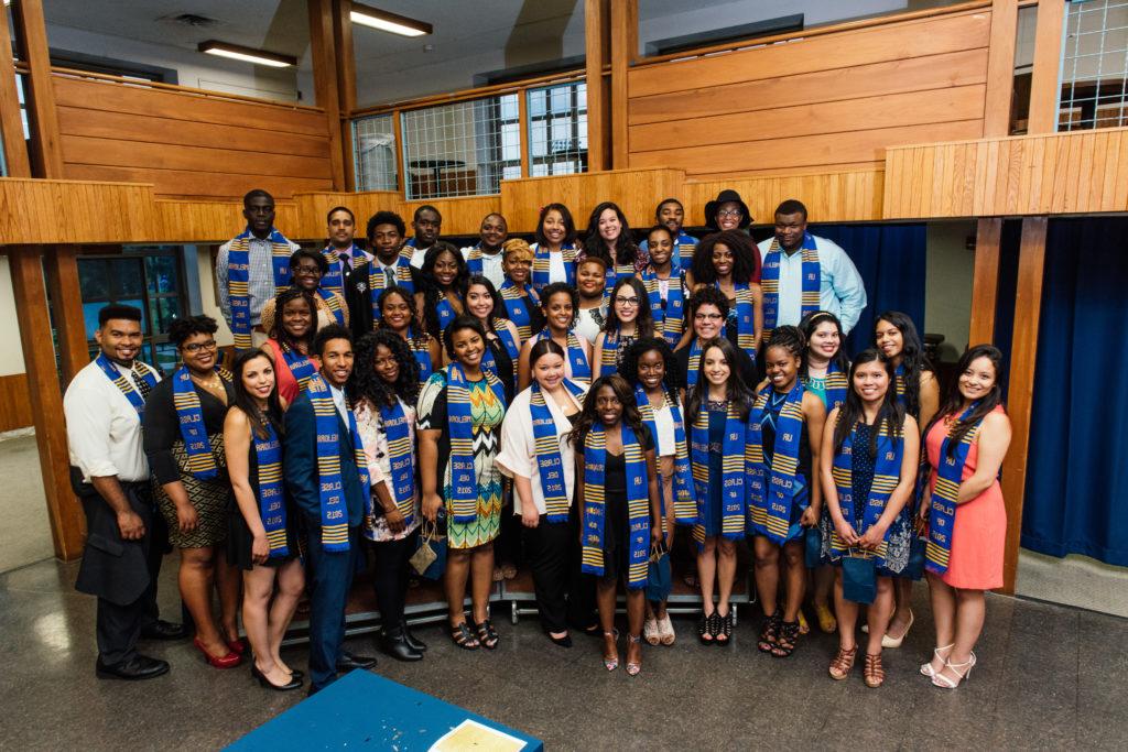 A University of Rochester student organization, group of students smiling for the camera wearing special graduation robes
