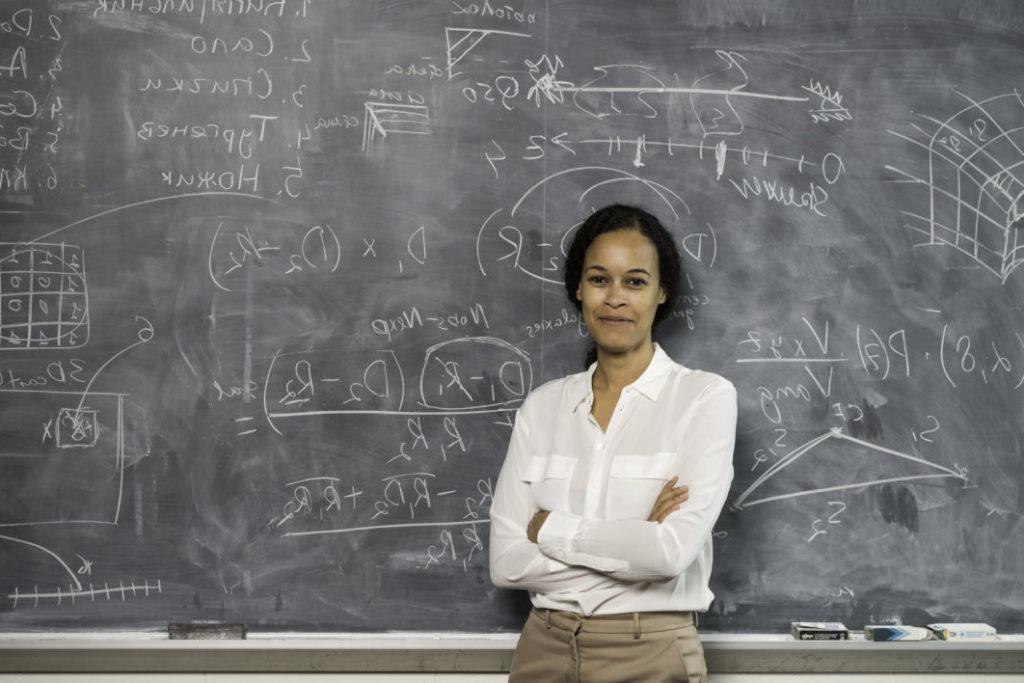 University of Rochester professor in front of her work on a chalkboard